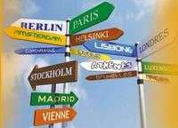 Panneau de signalisation avec les noms de grandes villes : Paris, Madrid...